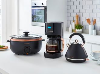 A matching rose gold slow cooker, coffee maker and pyramid kettle on a kitchen benchtop